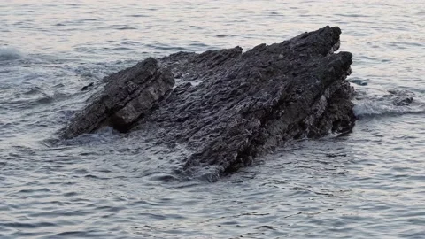 A strong current of water washes the stone into the sea. The waves break on the Stock Footage 215204928