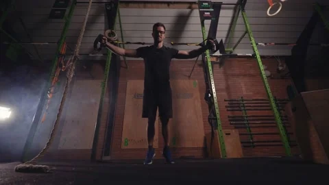 Strong dark haired male doing TRX Chest Fly exercise Stock Footage 131232432