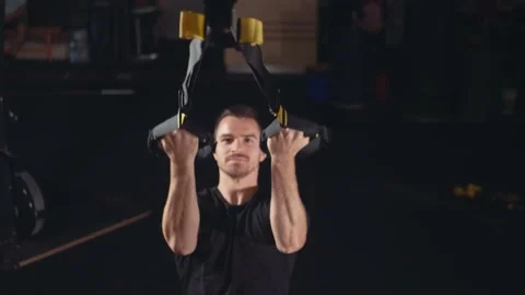 Strong dark haired male doing TRX biceps curl exercise Stock Footage 131232630