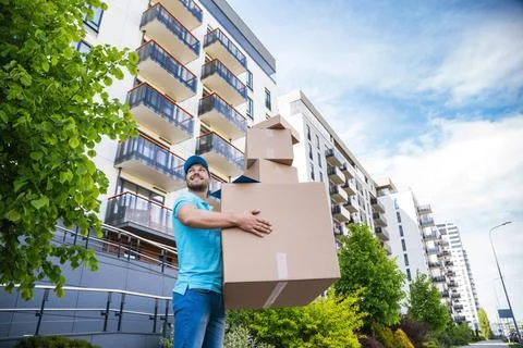 Strong delivery man holding a stack of a cardboard boxes Strong delivery m... 库存照片