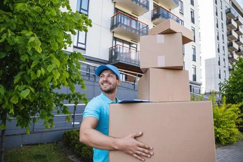 Strong delivery man holding a stack of a cardboard boxes Strong delivery m... Stock Photos