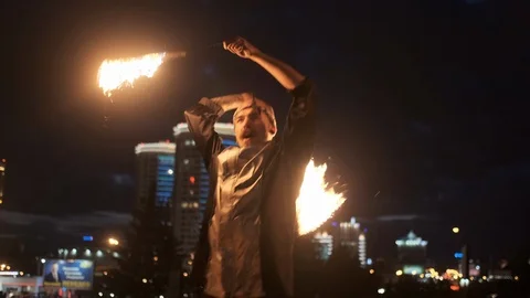 Strong expressive man perform tricks with glowing fire torches. He spinning and Stock Footage 120689776