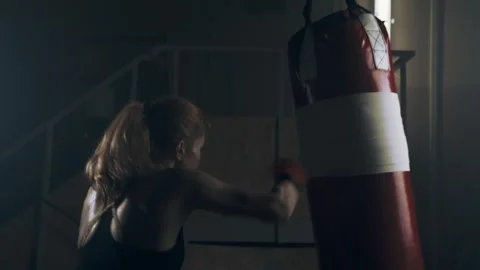 Strong female fighter practicing fast and strong hand strikes on a punching bag Stock Footage 273246309