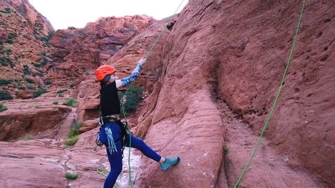 Strong Female Rock Climber Pulls Rope after Climbing at Red Rock Sandstone Cliff Stock Footage 114775562