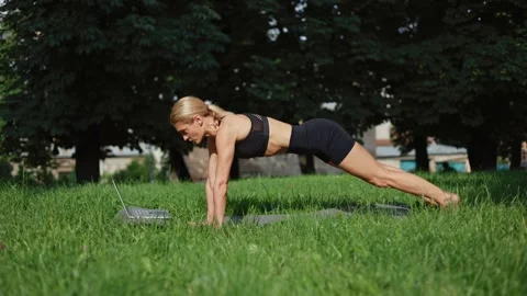 Strong female trainer using laptop for sport video lesson on fresh air Stock Footage 252123654
