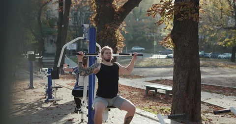 Strong fit couple doing pull ups together in an awesome outdoor gym. Man and Stock Footage 195258898