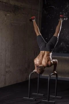 Strong fit man is using parallel bars in training at gym Stock Photos