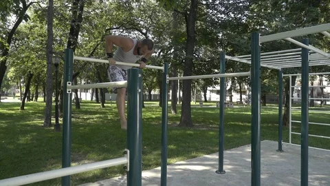 Strong guy demonstration exercise - chin ups with jumps over bar, gimbal shot. Video stock 93872704