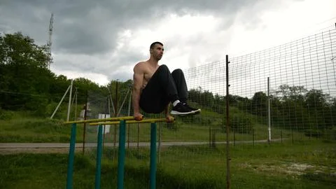 Strong guy training abdominal muscles on parallel bars at sports ground. Young Stock-Fotos