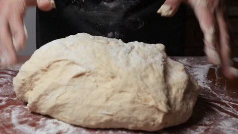 Strong hands knead the dough on the table closeup Stock Footage 124960144