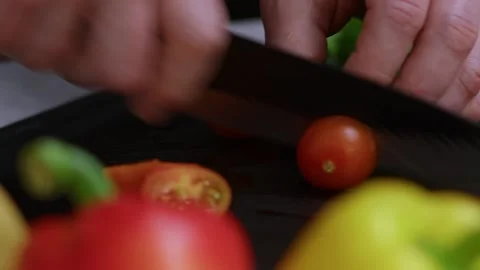 The strong hands of a man hold a knife and cut ripe cherry tomatoes with it Stock Footage 273013042