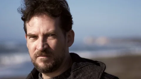Strong handsome man looking camera in front of the ocean slow motion closeup Stock Footage 107834993