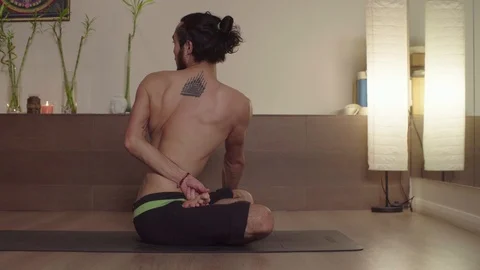 Strong handsome man practicing yoga - Ardha Padmasana, Twist Video stock 105908176