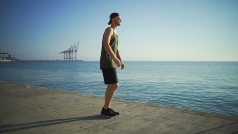 Strong healthy man do lunges exercises on sunny seaside pier rapid slow motion Stock Footage 78028471