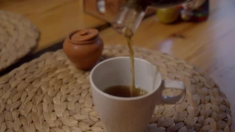 Strong herbal infusion is poured in thin stream from glass bottle into ceramic Stock Footage 221977614