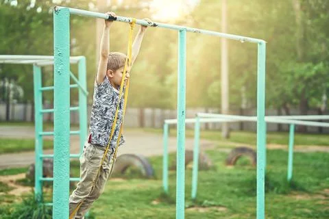Strong kid doing doing exercises with a fitness elastic band on sports ground 写真素材