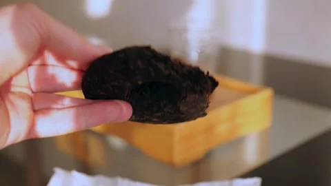 A strong male hand demonstrates pressed dark shu pu-erh. Chinese tea ceremony Stock Footage 218447448