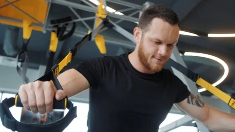 A strong man with beard tenses up while training hands in the gym on simulator. Stock Footage 129309414