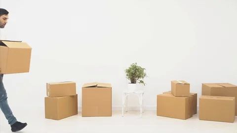 Strong man is carring a large moving box, full of items, isolated on white Stock Footage 121345399