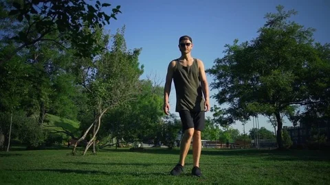 Strong man do ankle rotation exercises on sunny green meadow rapid slow motion Video stock 78037747