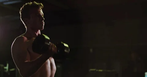 Strong man does bicep curls with dumbbells Stock Footage 83181996