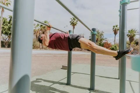 A strong man is doing Australian pull ups at a calisthenics outdoor gym in .. Stock Photos