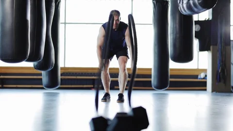 Strong man doing battle rope exercise in gym Stock Footage 108970330