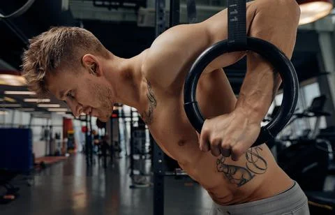 Strong man doing exercise on to gymnastic rings at gym. Fit male athlete Fotos de archivo