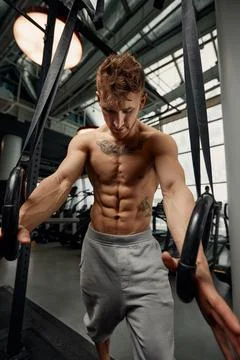Strong man doing exercise on to gymnastic rings at gym. Fit male athlete Fotos de archivo