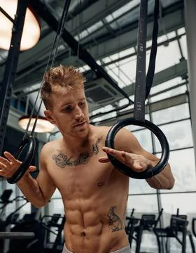 Strong man doing exercise on to gymnastic rings at gym. Fit male athlete Fotos de archivo