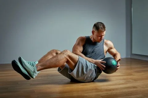 Strong man doing exercise with med ball. Photo of man perfect physique on grey Stock Photos