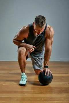 Strong man doing exercise with med ball. Photo of man perfect physique on grey Stock Photos