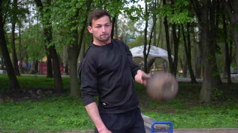 Strong man doing exercises with a kettlebell while holding her hands. Training Stock Footage 130387300
