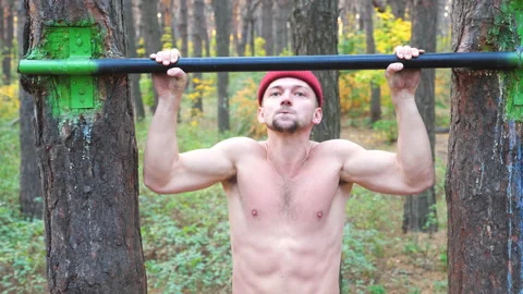 Strong man doing pull ups on horizontal bar with crazy expression on face. 動画素材 165812193