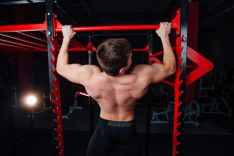 Strong man doing pull ups handsome athlete at gym. big confident muscular Stock Photos
