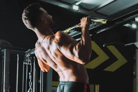 Strong man doing pull-ups on a bar in a gym Stock Photos
