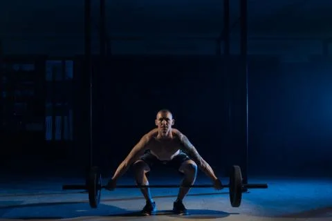 Strong man doing sit-ups with a barbell in the gym Stock Photos