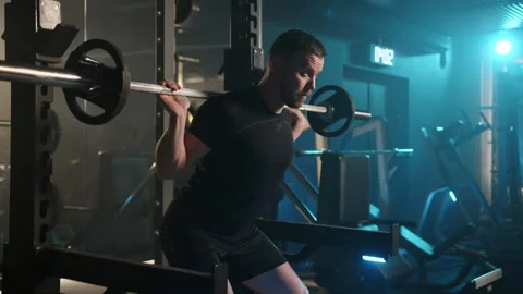 Strong Man Executing Barbell Squats with Precision in Modern Gym Stock Footage 269206014
