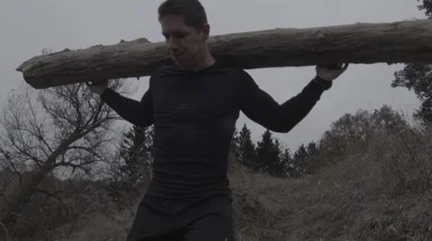 Strong man going downhill with a log on the shoulders (BMCC 2.5K - 2400x1350) Video stock 47958435