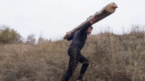 Strong man going uphill with a log on the shoulders (BMCC 2.5K - 2400x1350) Stock Footage 47943282