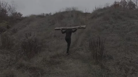 Strong man going uphill with a log on the shoulders (BMCC 2.5K - 2400x1350) 스톡 동영상 47945412