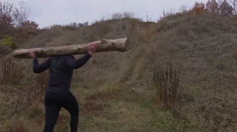 Strong man going uphill with a log on the shoulders (BMCC 2.5K - 2400x1350) Stock Footage 47968442