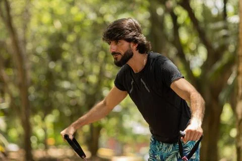 Strong man guy working out with elastic rubber bands at a park outdoors. Athl Stock Photos