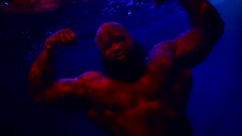 Strong man with large muscles is demonstrating brawny arms swimming underwater 動画素材 191980186
