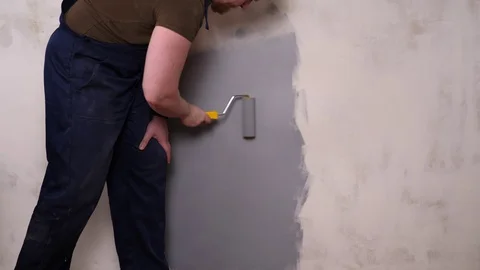 A strong man paints the wall with gray paint. Stock Footage 128813597