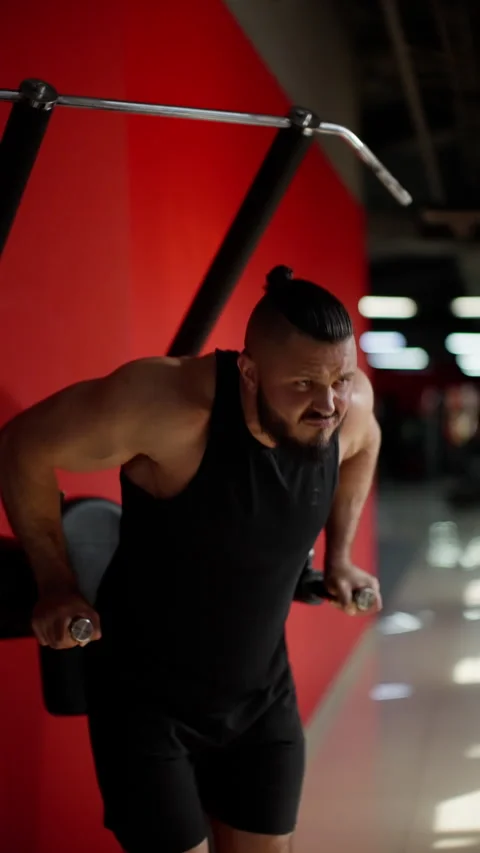 Strong man performing dips on parallel bars in a gym with red walls Stock-Footage 276187517