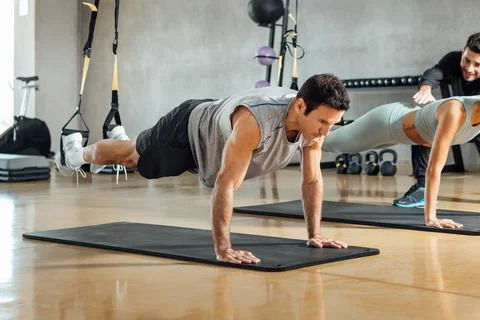 Strong man performing plank pose, suspensions training exercise at gym. Stock Photos