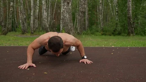 Strong Man Performing Push-ups in Nature Stock Footage 329599234