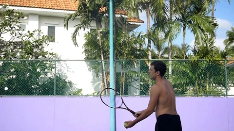 A strong man plays tennis without a T-shirt, gives the ball from above. Slow Stock Footage 88399894