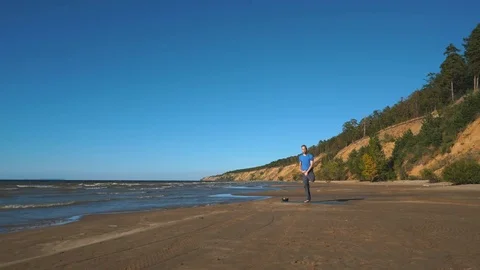 Strong man practicing difficult yoga pose on the beach Stock Footage 80864423